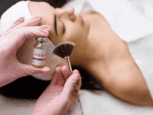Fase di applicazione PRX-T33 Applicazione professionale del gel PRX-T33 con pennello a ventaglio su viso di una paziente.