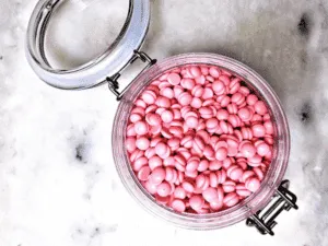 Barattolo aperto con granuli rosa di cera brasiliana utilizzati per la depilazione a caldo.