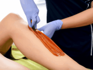 Estetista che applica cera brasiliana alle gambe durante un trattamento di epilazione professionale.