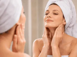 Donna esegue massaggio viso antirughe davanti allo specchio per rassodare mandibola e guance