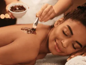 "Estetista applica una crema esfoliante su un cliente durante il trattamento peeling al corpo.