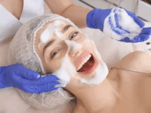 Estetista applica una schiuma esfoliante sul viso di una cliente durante il trattamento