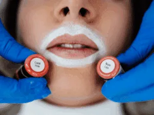 Scelta dei pigmenti per il trucco semipermanente labbra effetto volume, con tonalità nude e rosate confrontate sul viso della cliente.