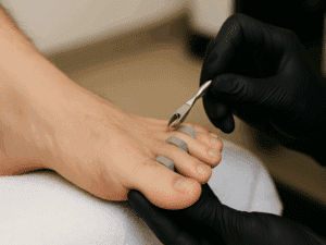 cura dei piedi maschili con pulizia cuticole e strumenti professionali