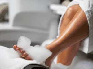Pedicure spa con bagno di schiuma per piedi e unghie curate.