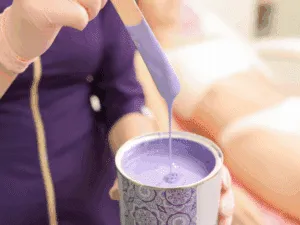 Preparazione della ceretta a caldo viola con spatola per un'applicazione precisa.