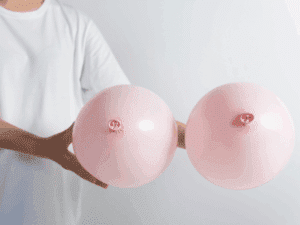 Come la dermopigmentazione dell’areola completa il seno ricostruito Due palloncini rosa tenuti da una persona, modellati per ricordare la forma del seno.