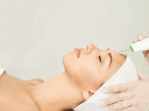 Trattamento professionale di pulizia del viso con dispositivo estetico su donna sdraiata
