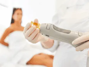Dettaglio manipolo laser alessandrite in preparazione Primo piano del manipolo del laser alessandrite durante la preparazione, con cliente pronta al trattamento sullo sfondo.