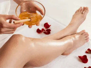 tecnica sugaring Applicazione della ceretta araba con pasta di zucchero sulle gambe per un’epilazione professionale