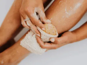 Esfoliazione della pelle del corpo con spugna naturale su gamba