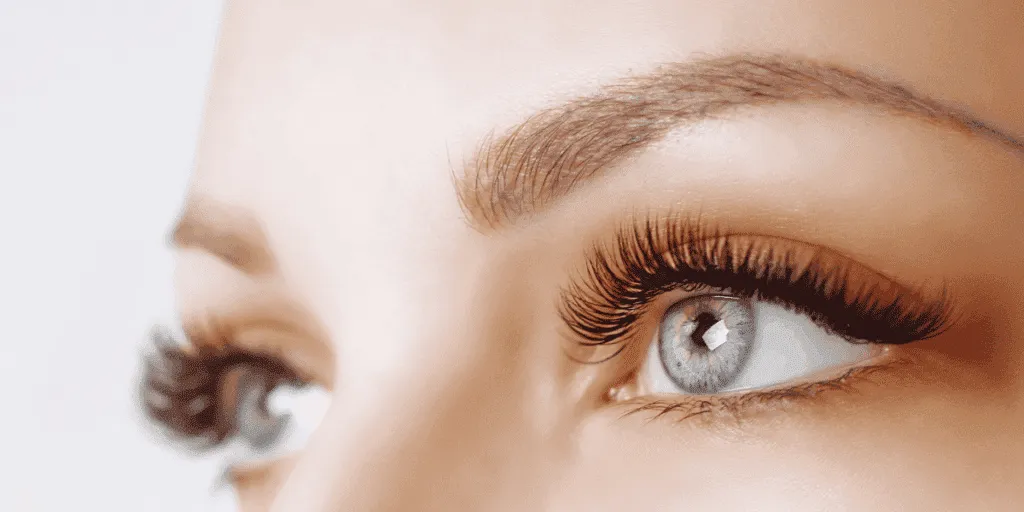 Primo piano di occhi femminili con estensioni ciglia professionali che mostrano un allungamento delle ciglia naturale e voluminoso.