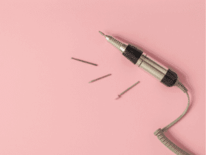 Fresa per unghie con punte intercambiabili su sfondo rosa.