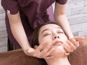 Una persona riceve un massaggio giapponese al viso, con un focus sul trattamento delle aree della mascella.