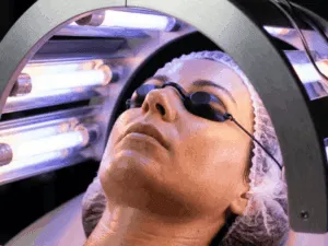 Primo piano di una sessione di abbronzatura viso con tecnologia a tubi UV e protezione oculare obbligatoria.