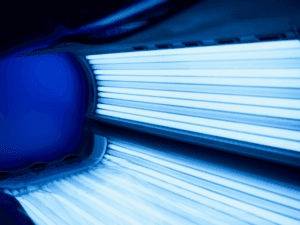 Dettaglio interno di un lettino solare professionale con tubi a bassa pressione attivi e luce blu intensa.