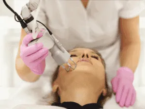 Operatrice estetica esegue un trattamento viso con laser ND:YAG su una cliente