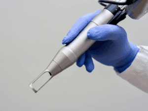 Manipolo laser nd yag in uso professionale Manipolo laser ND:YAG tenuto da un operatore con guanti per trattamenti estetici professionali