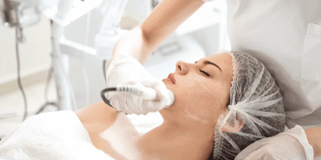 Trattamento laser viso per acne in corso su una donna, con l'operatore che applica il dispositivo sul viso.