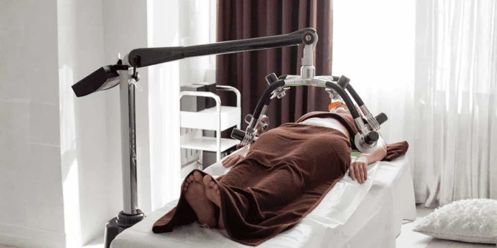 Persona sdraiata su lettino estetico durante trattamento corpo con macchina laser yag professionale in un centro estetico