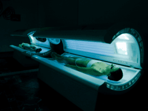 Cabine solarium moderne con clienti distesi su lettini abbronzanti professionali in un ambiente estetico rilassante.