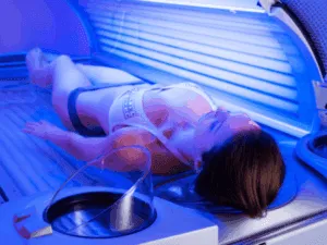 Donna distesa in un lettino solare professionale per una sessione di abbronzatura integrale uniforme.