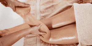 Operatore che esegue un massaggio linfodrenante alle gambe con tecnica di linfodrenaggio manuale per drenaggio linfatico, trattamento linfodrenante professionale utile per ritenzione idrica, cellulite e gambe gonfie in un centro estetico.