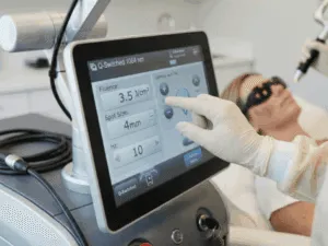 Professionista che utilizza laser per la rimozione di macchie cutanee da viso di paziente.