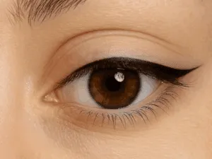 Occhio marrone con eyeliner semipermanente sottile e definito applicato sulla palpebra superiore.