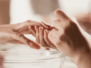 Estetista che esegue una manicure estetica con ammollo delle mani e cura delle cuticole.