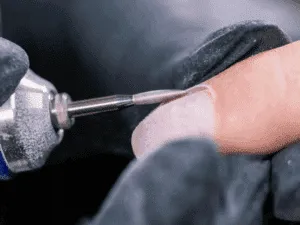 Dettaglio ravvicinato della punta fresa mentre rifinisce il giro cuticole durante una manicure russa.