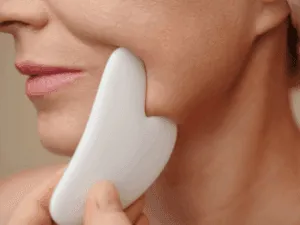 Massaggio viso antirughe con pietra gua sha lungo la linea mandibolare