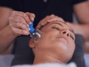 Massaggio viso con coppette per effetto lifting naturale. Operatore che esegue cupping viso con coppetta facciale per stimolare tessuti, drenare liquidi e migliorare ossigenazione cutanea.