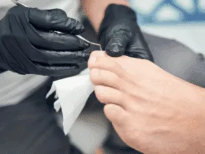 Tecnica di pedicure a secco con strumento metallico su piede ben curato.