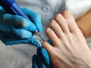 Estetista che lima i piedi di una cliente durante un pedicure professionale in centro estetico.
