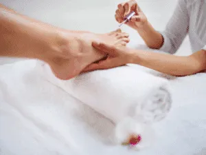 Applicazione di smalto durante pedicure professionale in centro estetico.