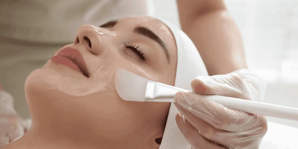 Applicazione di peeling chimico viso con pennello professionale durante trattamento estetico