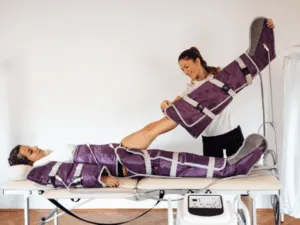 pressoterapia gambe Donna durante un trattamento di pressoterapia alle gambe con gambali viola, mentre l’estetista regola il dispositivo per migliorare drenaggio linfatico, microcircolo e benefici pressoterapia.