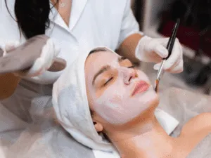 Pulizia del viso professionale con maschera applicata a pennello Estetista applica una maschera cremosa sul viso di una cliente durante una pulizia viso professionale con pennello.