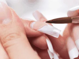 Un’estetista applica il gel acrilico per creare unghie lunghe e resistenti con un effetto naturale e curato.