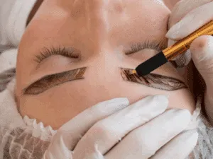 Trattamento di ritocco microblading sopracciglia con penna manuale e pigmento, eseguito da professionista con guanti sterili.