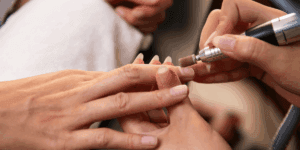 Operatrice estetica che utilizza la fresa per pulire e preparare l’unghia durante una manicure russa a secco.