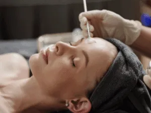 Trattamento di peeling enzimatico eseguito su una donna con pennello a ventaglio durante una seduta professionale.