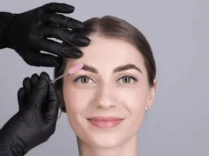 Estetista che applica la tecnica per infoltire le sopracciglia utilizzando strumenti di precisione su una cliente.