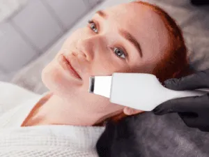 Spatola ultrasuoni in azione per esfoliazione profonda. Trattamento di pulizia del viso con spatola ultrasuoni professionale su una cliente in centro estetico