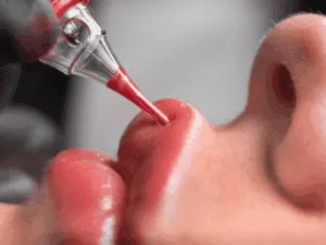 Dettaglio del trattamento di tatuaggio labbra con tecnica lip blush, mentre il pigmento rosato viene applicato con precisione.