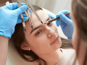 Progettazione della forma delle sopracciglia prima del trattamento di microblading, con misurazioni precise e disegno a matita per un risultato simmetrico.