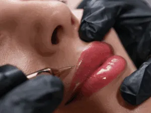 Dermopigmentazione labbra durante il trattamento di lip blushing, con professionista che applica pigmento tramite dermografo.
