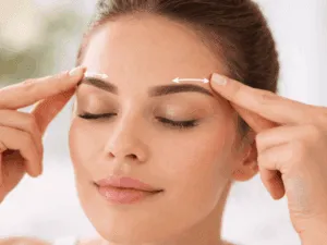 Donna che esegue un massaggio lifting sulle sopracciglia con movimenti delicati per distendere la fronte e aprire lo sguardo.
