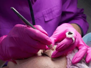 Operatrice estetica esegue trattamento di microblading sopracciglia con penna manuale e pigmento, tecnica professionale di dermopigmentazione.